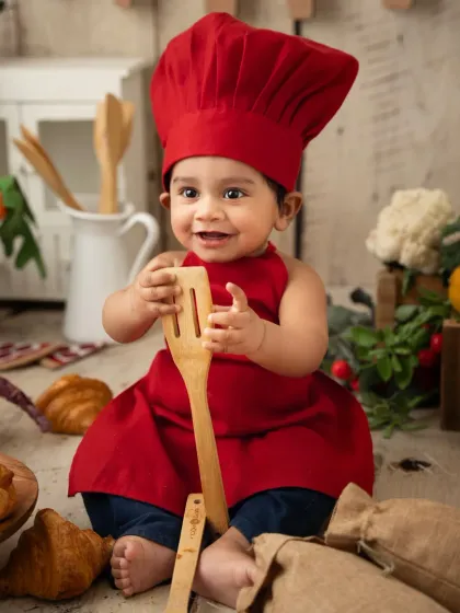 A little chef plays with a wooden spatula, surrounded by croissants and vegetables. Themed baby photoshoots are so much fun to style.