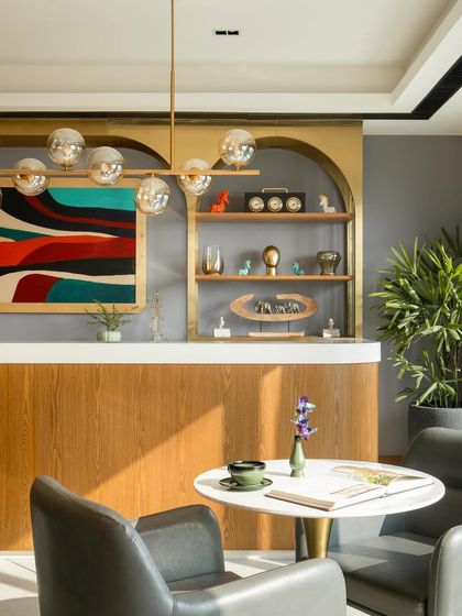 The reception and lounge area at Citadines creates a welcoming first impression. A clean-lined counter is set against a backdrop of brass-framed shelves, with a colorful abstract painting adding a touch of artistic flair.