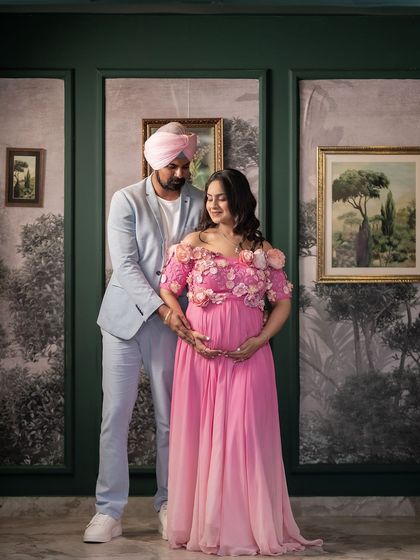 A beautifully posed portrait of the couple at their baby shower. They stand in front of an elegant, artistic backdrop, creating a formal and timeless memory of the celebration.