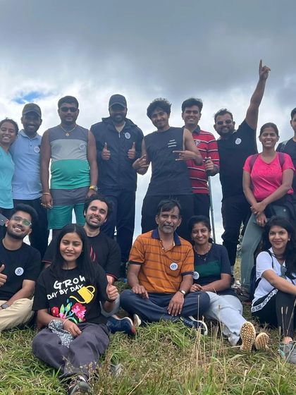 A diverse group of trekkers giving thumbs up at the Nishani Motte peak. Our treks are for everyone with a spirit for adventure.