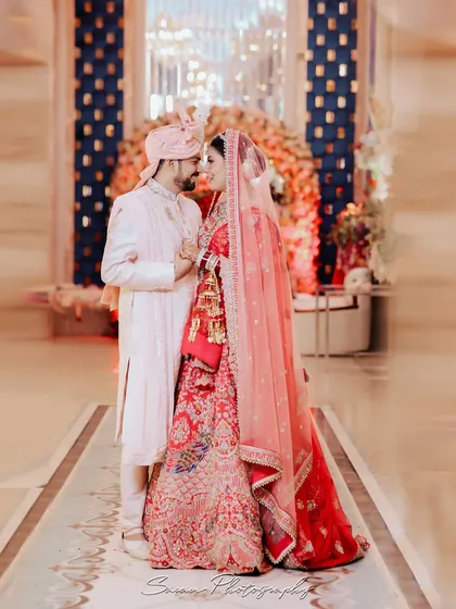 A romantic full-length portrait of the couple on their wedding day, standing close in a beautifully decorated hall.