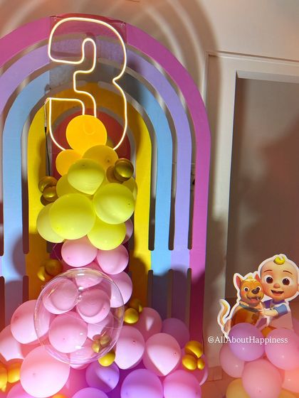 A close-up of the rainbow arch backdrop with a neon number '3', part of our colorful and playful Cocomelon party decor.