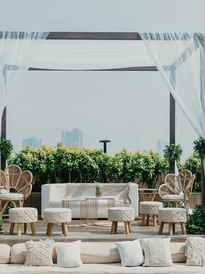 A bohemian-inspired lounge area with macrame pillows, wicker chairs, and draped fabric for a relaxed vibe.