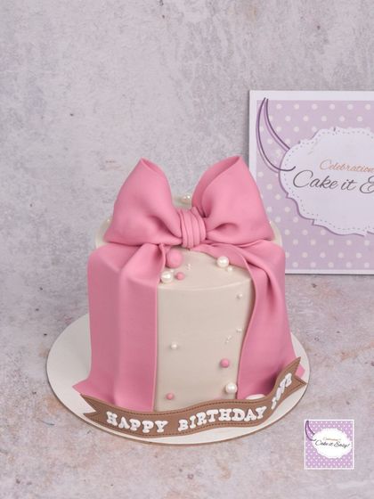A simple and elegant cake featuring a large, beautiful pink fondant bow. This shows that a cake doesn't always need figurines to make a statement.