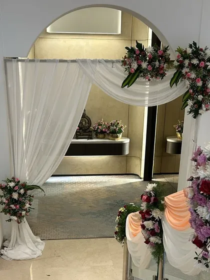This entranceway for a reception features soft white drapes and floral arrangements. This type of decor helps create a beautiful transition for guests as they move into the main event area.