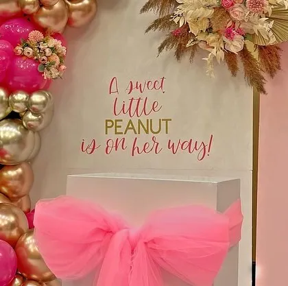The setup features a large pink bow on a pedestal, adding a delicate and feminine touch to the "sweet little peanut" theme.