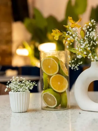 A fresh and zesty centerpiece using sliced lemons in a glass vase, perfectly complementing the yellow and green color scheme of the event.