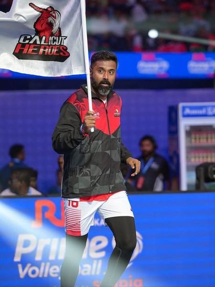 A player from the Calicut Heroes enters the court at the Prime Volleyball League. We design and execute grand player entries with spotlights and flags to build match-day excitement.