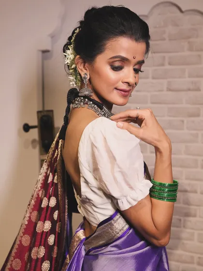A close-up of the model's profile, highlighting the traditional jewelry and the soft, romantic makeup.