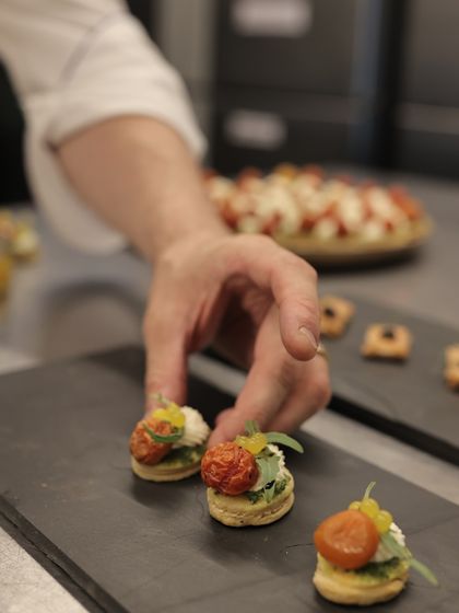 A chef's hand carefully places a canapé on a slate platter, showcasing the precision and artistry of our kitchen.
