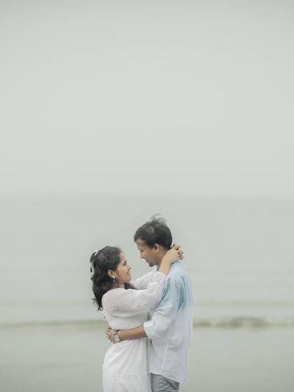A minimalist and serene portrait of a couple embracing against the open sea and sky, creating a feeling of peaceful intimacy.