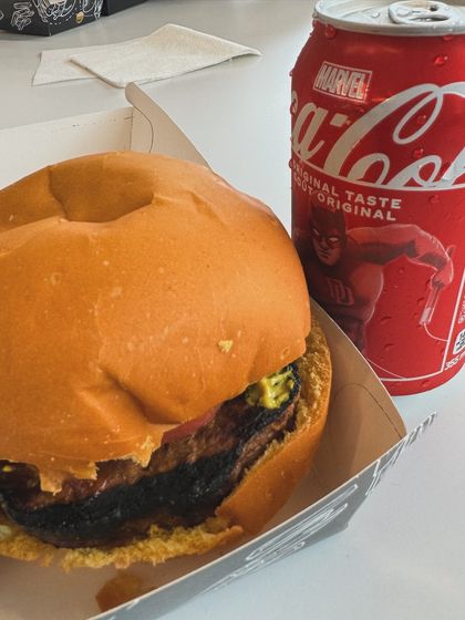 A close-up shot of a burger and a Marvel-themed Coca-Cola can, a classic food UGC image.