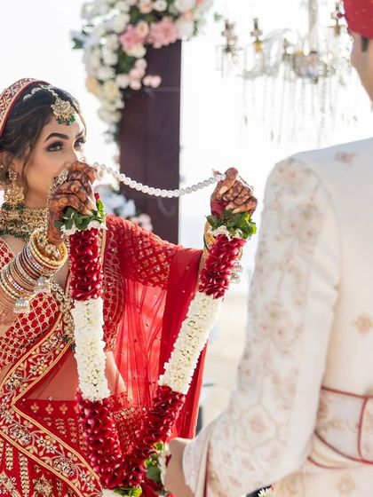 The bride's playful expression as she prepares to place the varmala on her groom. We capture the fun and personality in every wedding ritual.
