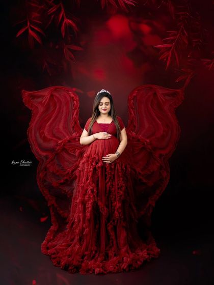 A vision in red. This portrait uses a deep, moody red background to complement the dramatic ruffled gown, creating an image that is both powerful and romantic.