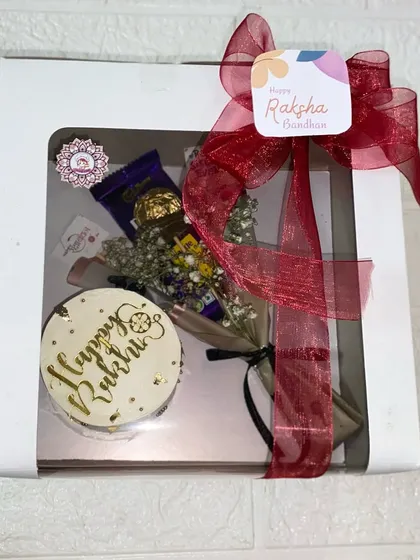 All packed and ready to gift! This is our elegant gold-scripted Rakhi bento cake and chocolate bouquet, presented in a window box and tied with a festive red ribbon.