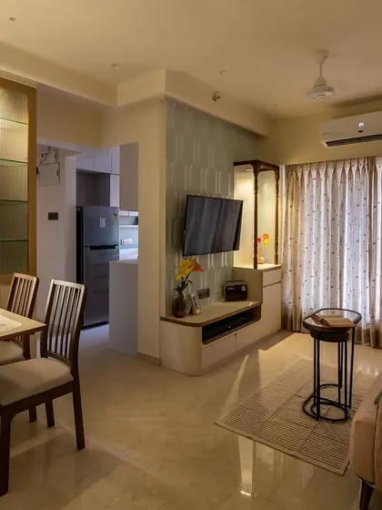 A night-time view of the living room with the fold-down dining table, showing how the space transforms with integrated lighting in the cabinetry.