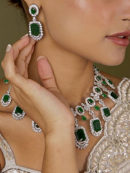 A close-up of our emerald and diamond bridal set. This image highlights the stunning rectangular emeralds surrounded by a halo of sparkling American diamonds in the earrings and necklace.