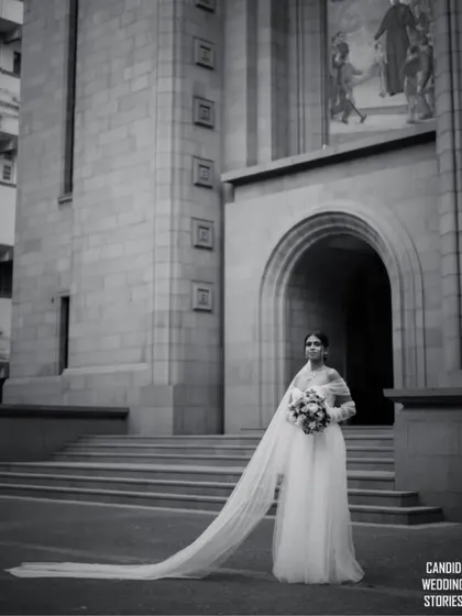 The timeless elegance of a bride. This portrait, shot in classic black and white, highlights the serene beauty and anticipation before the ceremony, showcasing our artistic approach to bridal photography against a stunning architectural backdrop.