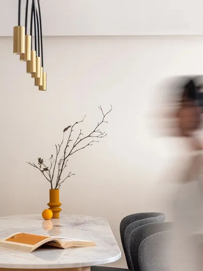 This artistic shot captures the clean aesthetic of the dining area, highlighting the form of the vase and the elegant pendant light.