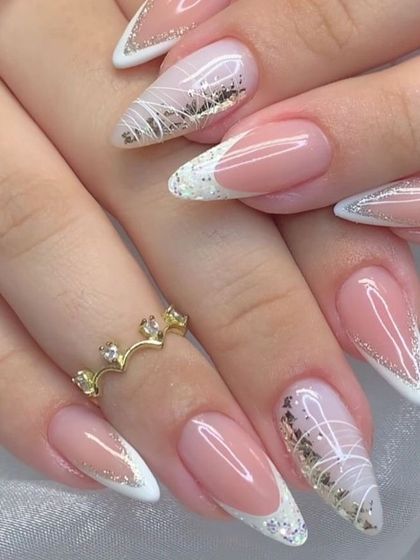 An elegant and intricate French manicure on long almond nails. This design features white tips with delicate white line art and gold and silver foil accents.