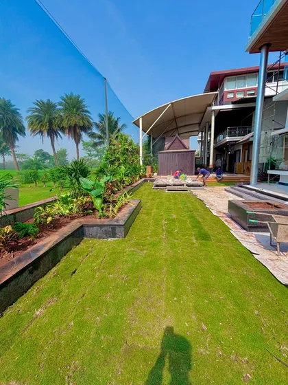 The completed lawn and garden area at the Lodha villa. This shows the final result, with the green grass connecting the house to the surrounding golf course.
