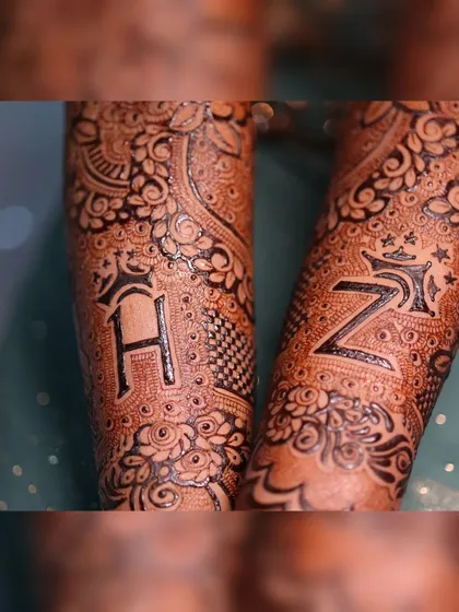 A close-up of the bold initials 'H' and 'Z' on the forearms, surrounded by intricate floral work.
