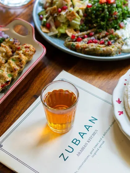 A shot for Cafe Zubaan in Bangalore, focusing on their menu and a glass of tea alongside a kebab platter. This style of photography helps set the scene for a restaurant.