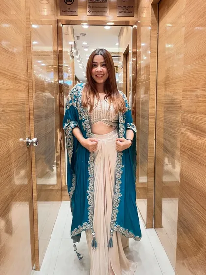 Don’t just stand out, stand in style. This stunning Indo-Western dhoti and cape set in teal and beige is the perfect example of modern ethnic fashion.