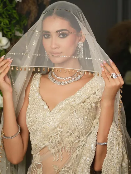 A close-up of the bride holding her veil, drawing attention to her delicate hands, stunning rings, and the intricate details of her diamond jewellery.