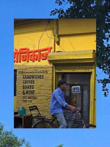 A man on a bicycle in front of a bright yellow shop named 'Veronica's'.