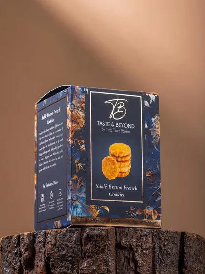 A moody, rustic shot of Taste & Beyond's Sablé Breton French Cookies box, placed on a tree stump. This styling gives the product an earthy, artisanal feel.
