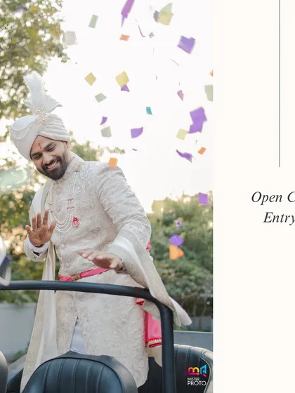 The groom makes a cool and modern entry in an open-top car, waving to guests as confetti flies.