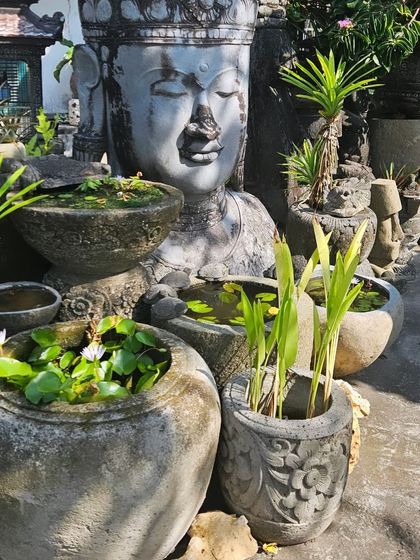 A collection of stone water-lily pots and a large Buddha statue, sourced to create an authentic and serene garden atmosphere.