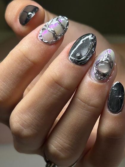 A close-up of an avant-garde 3D chrome nail art set. This design features sculpted, liquid-metal-like silver details over a pearlescent, multi-tonal base.