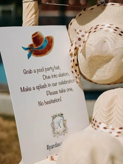 A close-up of the personalized sign for the party hats, inviting guests to "Make a splash in our celebration". It’s these little touches that make an event feel personal.