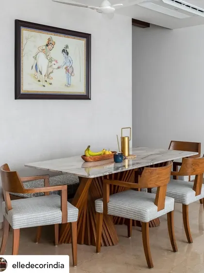 The dining area of 'House Nandini', featured in Elle Decor. The space combines a modern marble-topped table with classic wooden chairs, all under a piece of traditional Indian art, reflecting our blend of styles.