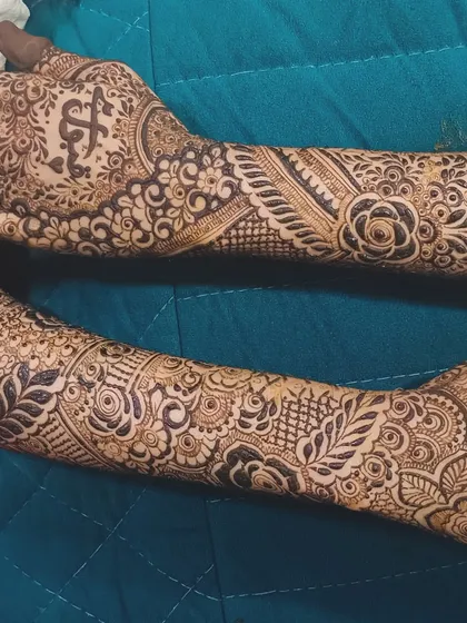 This design shows another way to incorporate initials, with one on each palm, balanced by dense floral and traditional patterns.