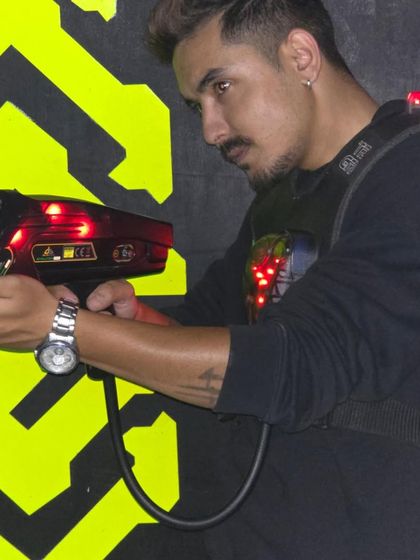A player takes aim in the laser tag arena, with the neon yellow patterns on the wall providing a cool backdrop.