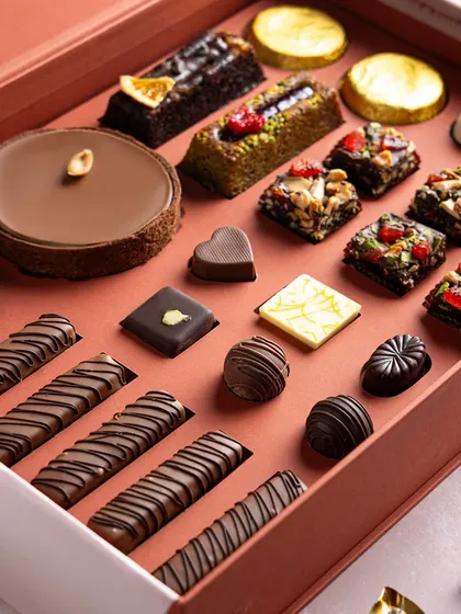 A premium gift box filled with an assortment of my finest creations, including chocolate tarts, financier bars, Belgian pralines, and fruit-topped brownies. This is a true connoisseur's box, offering a complete taste of my patisserie skills.