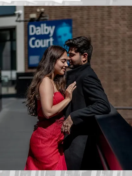 An intimate and romantic moment on a city balcony. The close embrace and soft expressions create a feeling of a private world amidst the bustling city of London.