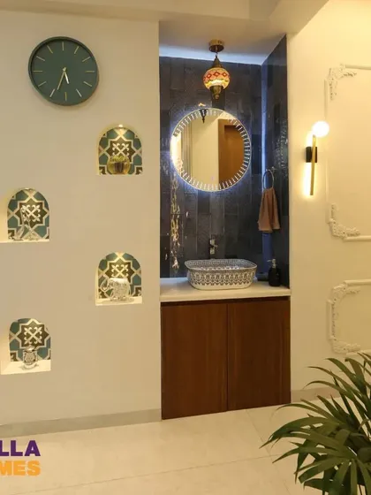 The wash basin area is designed as a feature in itself, with a stylish printed bowl, a backlit mirror, and decorative arched niches for displaying small artifacts, adding a touch of Moroccan-inspired flair.