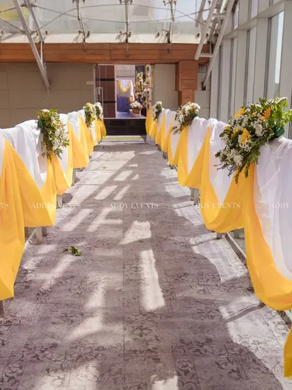 A beautifully draped walkway with yellow and white fabric, creating an elegant and sunny passage for guests.