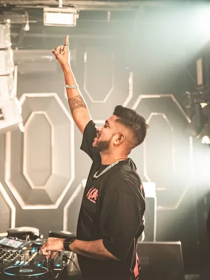 Pointing to the sky at Glitte, caught in a beam of light. A classic DJ moment that captures the peak energy of the night.