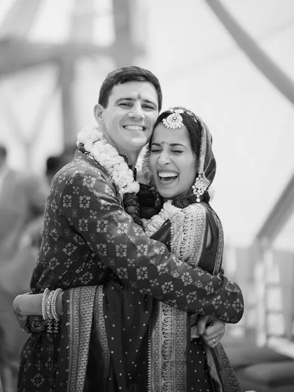 A beautiful, spontaneous hug between a cross-cultural couple right after their ceremony. This black and white photograph freezes a moment of pure happiness and relief, highlighting the universal language of love.
