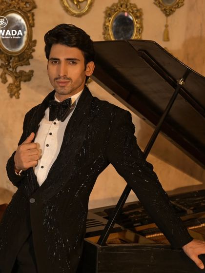 A confident pose in the black sequined tuxedo, highlighting the fit and the intricate texture of the fabric.