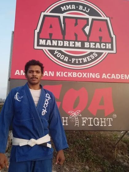 Standing in my Gi in front of the AKA Mandrem Beach sign, home of the Goa Beach Fight. Ready for competition.