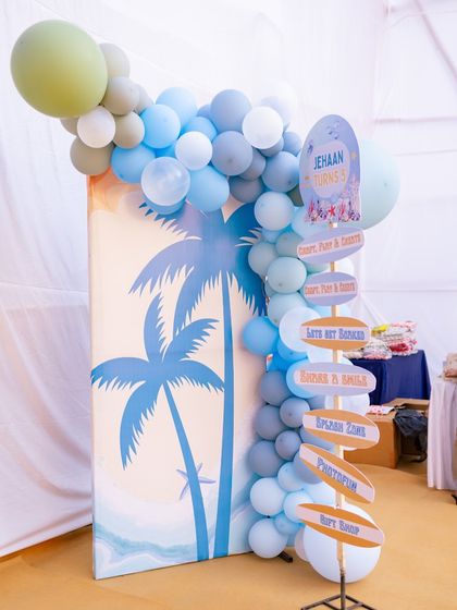A custom directional signpost points guests to the different fun zones of the party, like the 'Arts N' Krafts' corner, 'Splash Zone', and 'Photobooth'. It's a fun and practical decor element.
