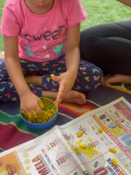 A child explores the texture of colored pasta, a fantastic fine motor and sensory activity. The simple act of scooping and pouring is deeply engaging for toddlers and helps develop hand-eye coordination.