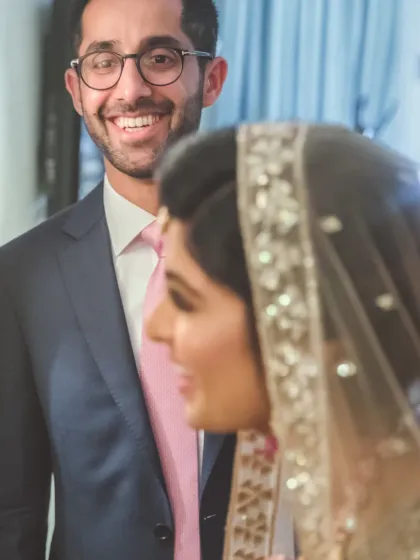 A "first look" moment filled with emotion, capturing the groom's joyful smile as he sees his bride for the first time.