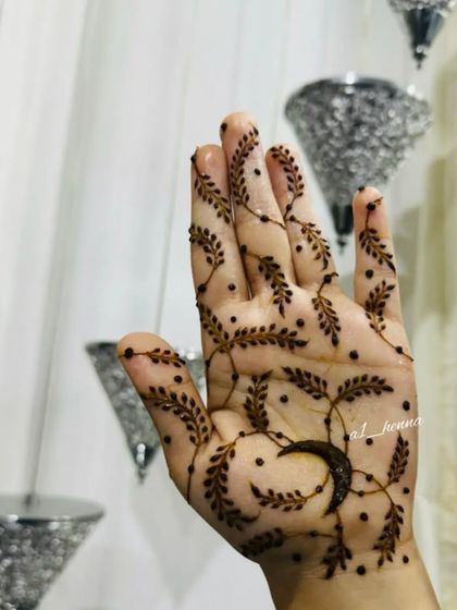 A close-up of the minimalist moon and vine design on a single hand.